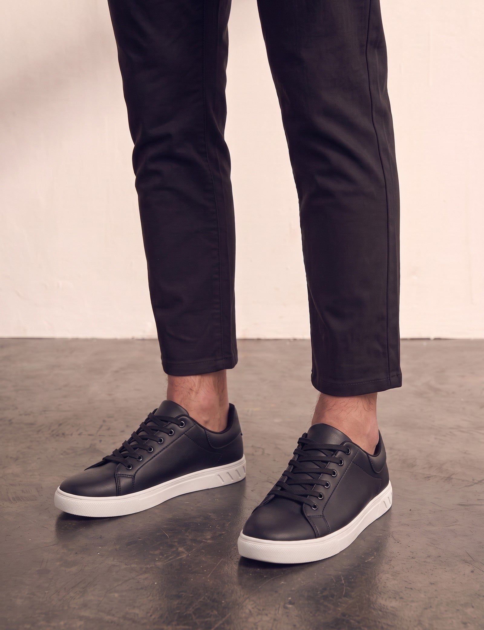 Men's Black Faux Leather Minimalist Low-Top Trainers, three-quarter front view of the shoes, worn.