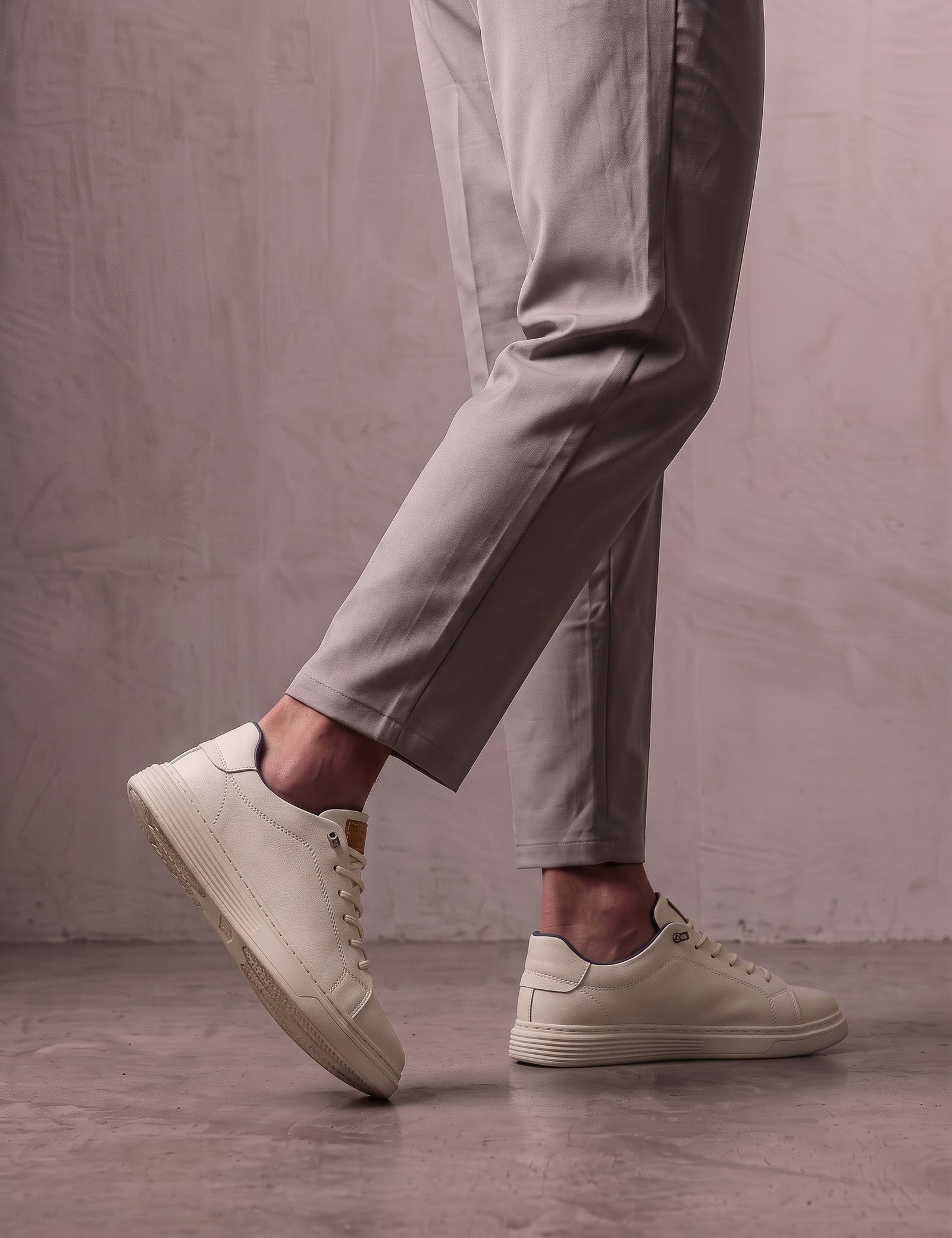 Men's Taupe Faux Leather Low-Top Trainers, the shoes in mid-step, showing the sole.