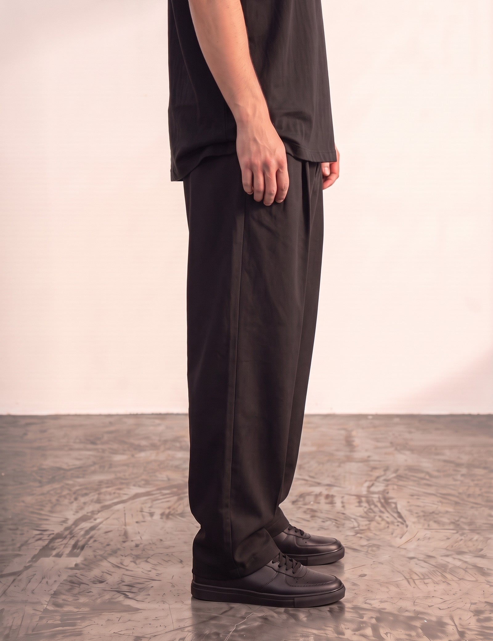 Men's Black Wide Leg Pleated Trousers, side view from the waist down.