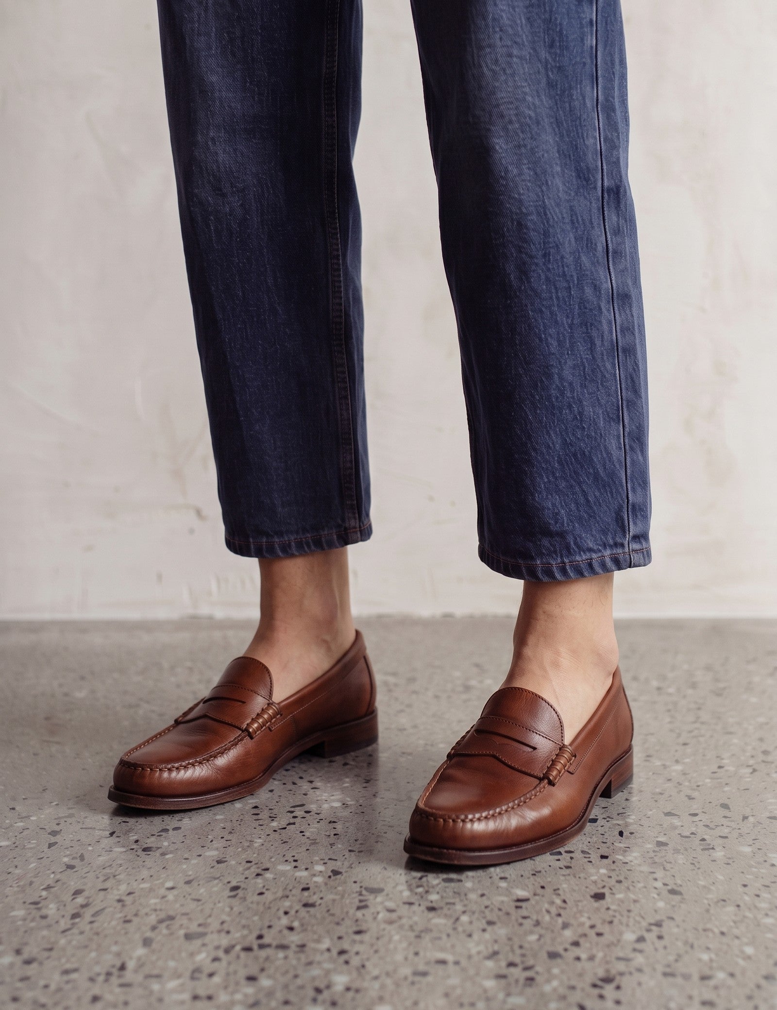 Men's Brown Penny Loafers with Moccasin Stitching, three-quarter front view of the shoes, worn.