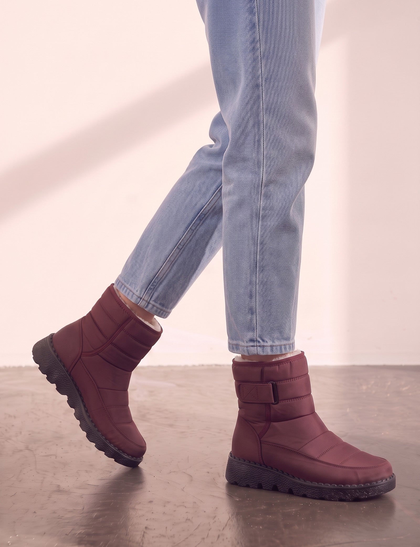 Men's Burgundy Quilted Snow Boots with Ankle Strap, the shoes in mid-step, showing the sole.