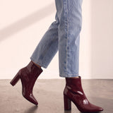 Women's Burgundy Patent Pointed Block Heel Ankle Boots, the shoes in mid-step, showing the sole.