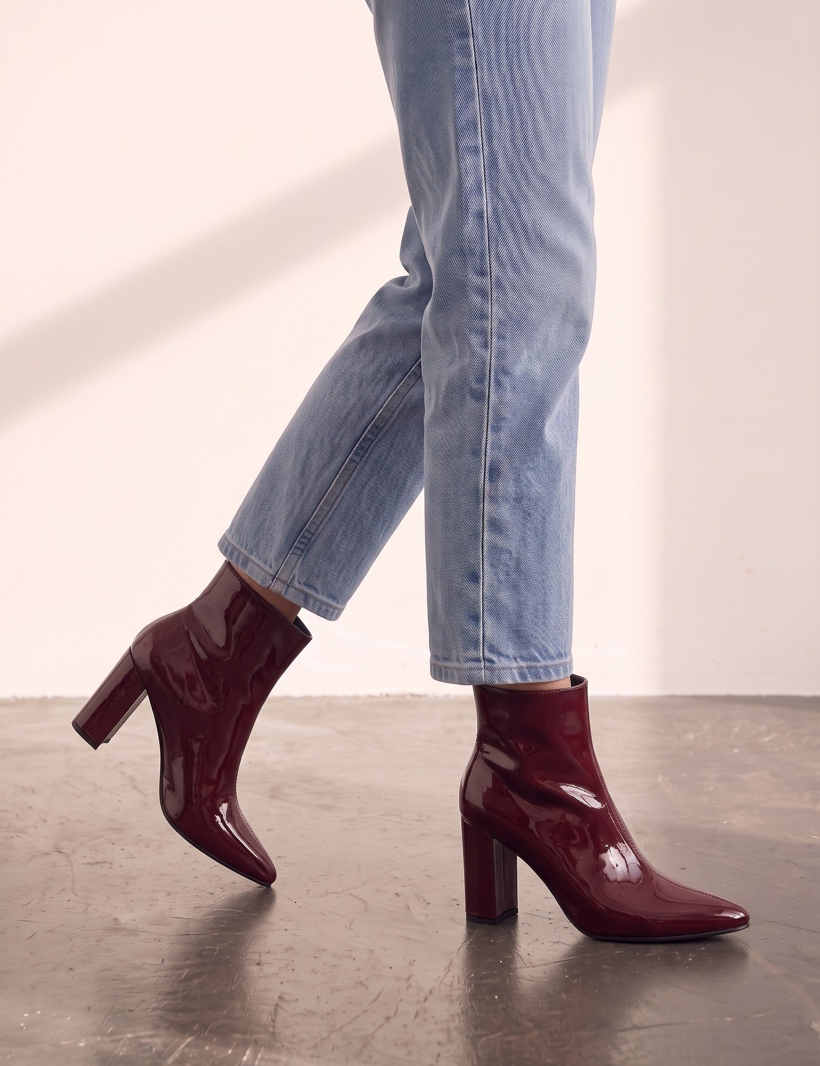 Women's Burgundy Patent Pointed Block Heel Ankle Boots, the shoes in mid-step, showing the sole.