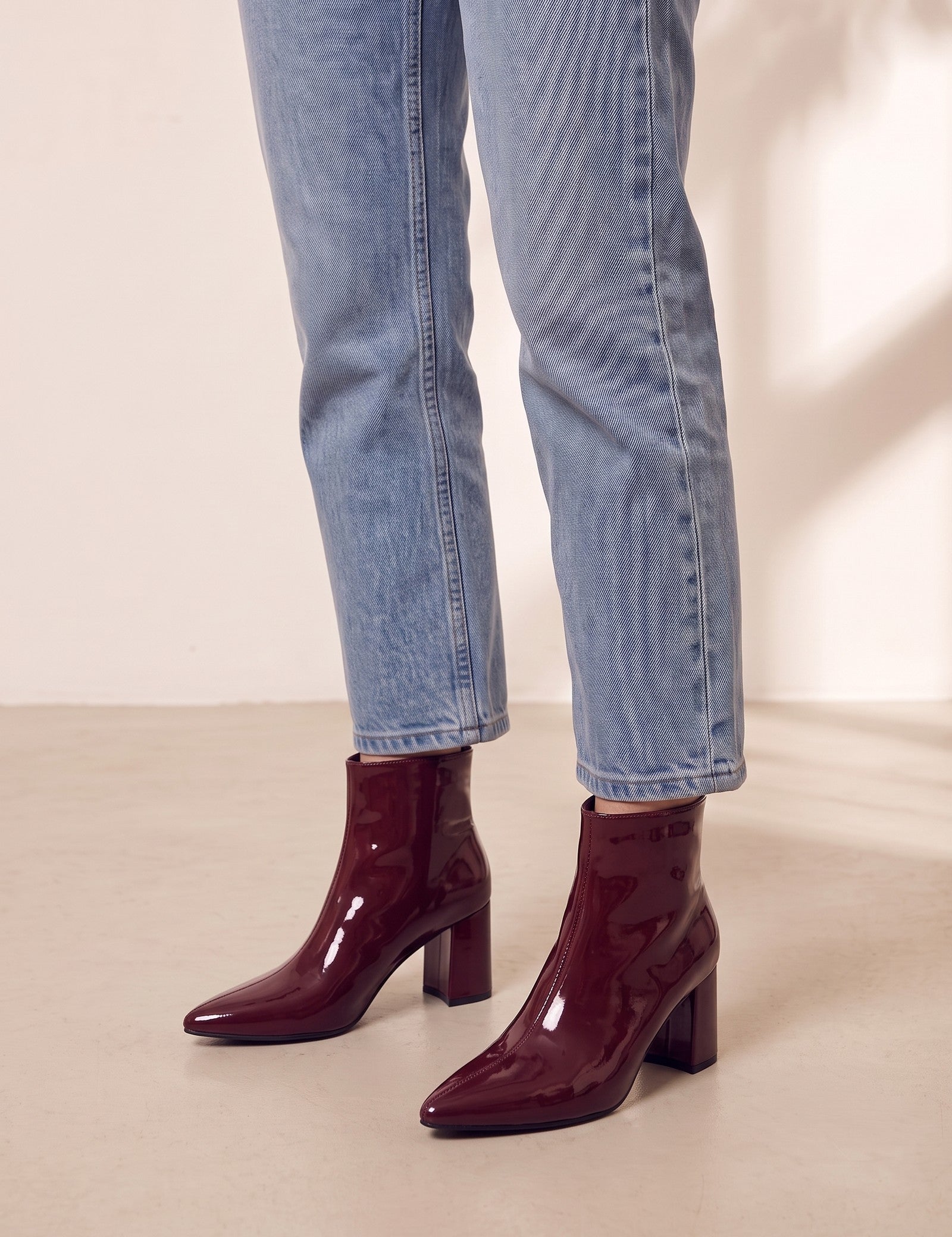 Women's Burgundy Patent Pointed Block Heel Ankle Boots, three-quarter front view of the shoes, worn.