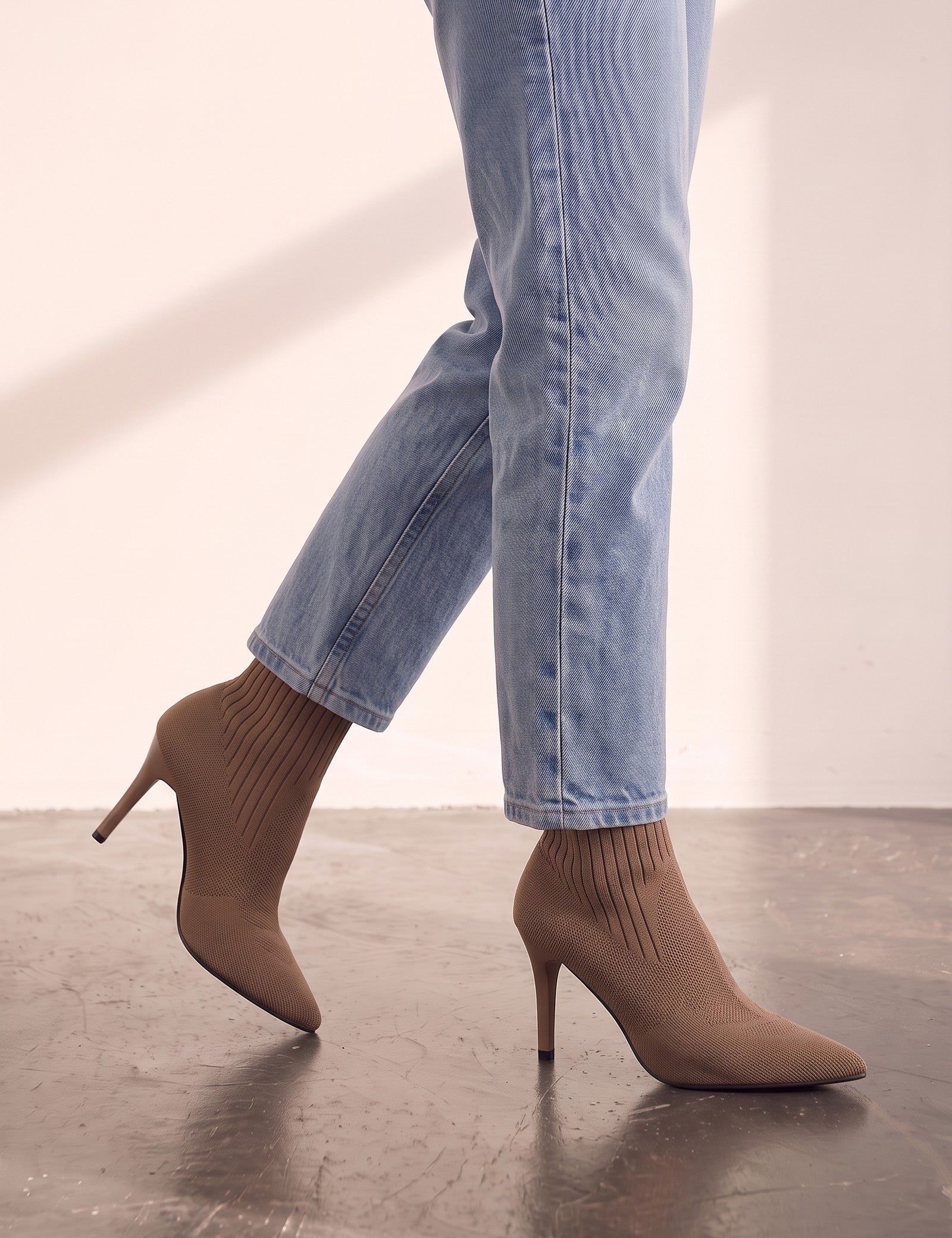 Women's Taupe Ribbed Knit Stiletto Sock Boots, the shoes in mid-step, showing the sole.