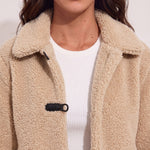 Women's Beige Teddy Jacket with Black Toggle Fastenings, close-up of the upper body.