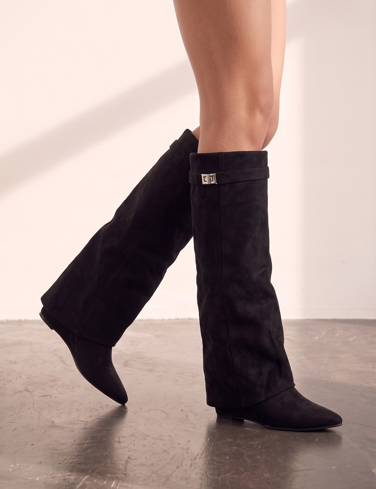 Women's Black Pointed-Toe Fold-Over Knee-High Boots, the shoes in mid-step, showing the sole.