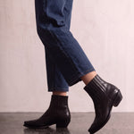 Women's Black Western Ankle Boots with Pointed Toe, the shoes in mid-step, showing the sole.