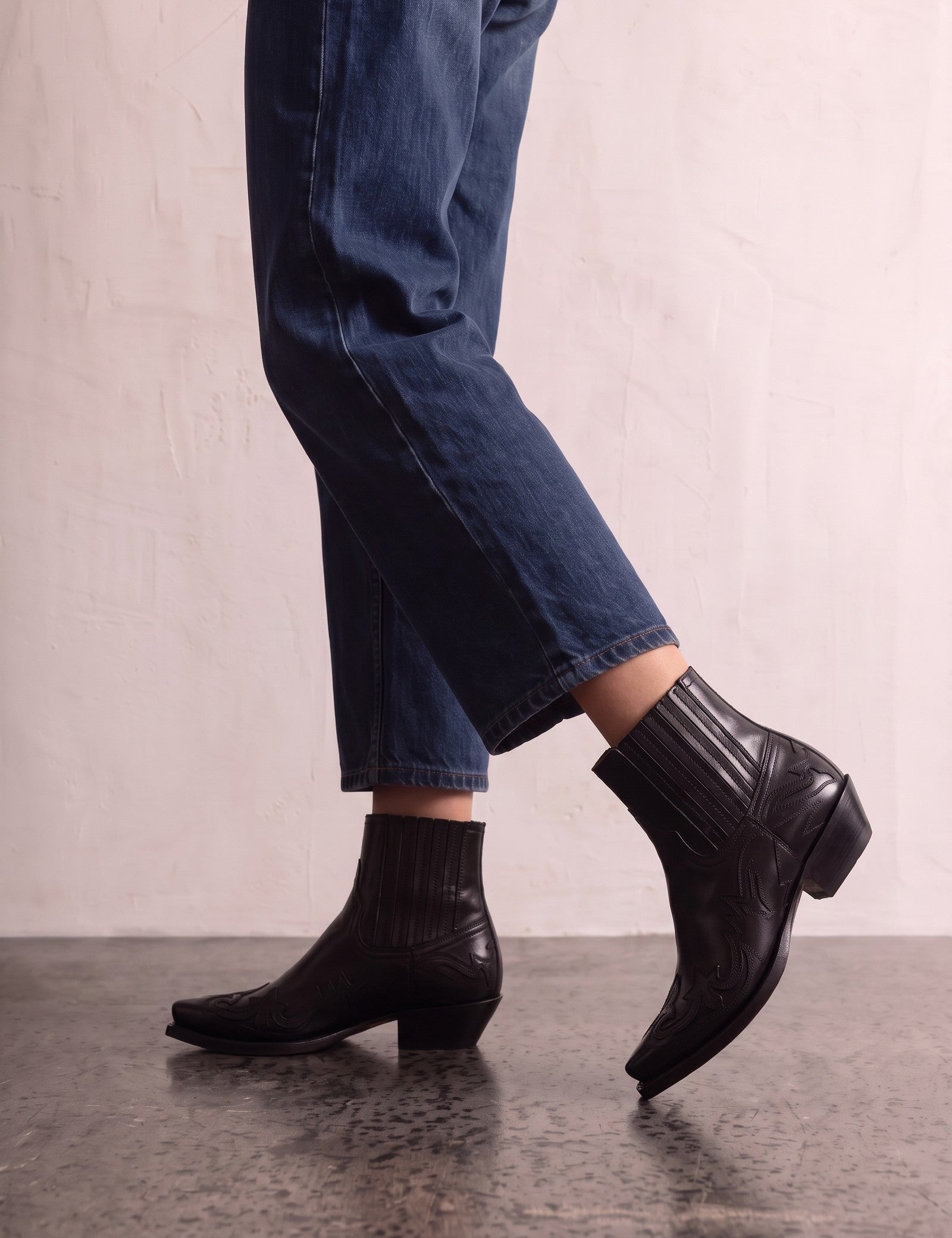 Women's Black Western Ankle Boots with Pointed Toe, the shoes in mid-step, showing the sole.