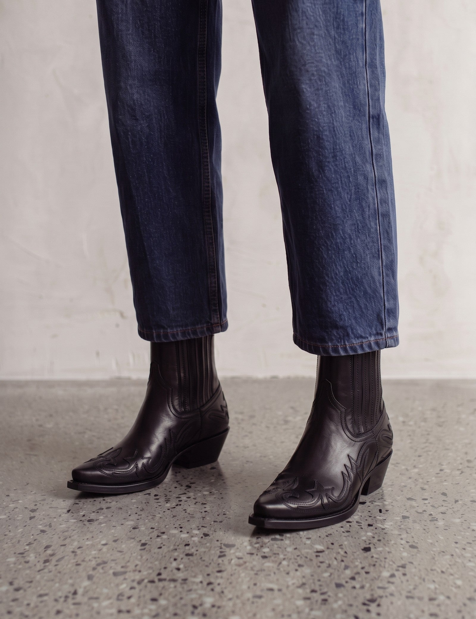 Women's Black Western Ankle Boots with Pointed Toe, three-quarter front view of the shoes, worn.