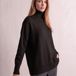 Women's Relaxed Fit Roll Neck Jumper in Black, three-quarter view from the left, full length.