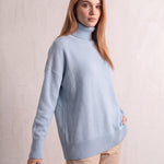 Women's Relaxed Fit Roll Neck Jumper in Light Blue, three-quarter view from the left, full length.